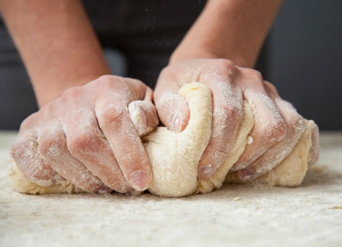 Woman's hands knead dough on a table